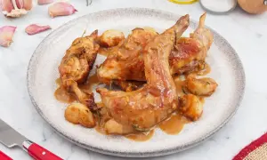 Plato de conejo al ajillo con trozos de ajo y romero. Una delicia para aprender cómo hacer conejo al ajillo.