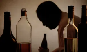 Flera flaskor alkohol framför en person i silhuett. Bilden illustrerar utmaningar med alkohol och arbetsgivarens rehabiliteringsansvar.