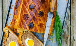 Pâté de Pâques doré, décoré d'étoiles, avec des œufs entiers au cœur. Une recette festive prête à être dégustée.