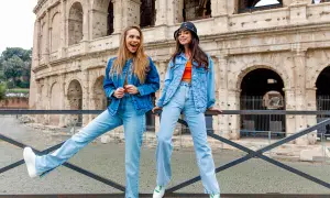 Dwie kobiety w strojach w kolorze denim pozują przed Koloseum. Jedna ma rozpuszczone włosy, druga nosi kapelusz.