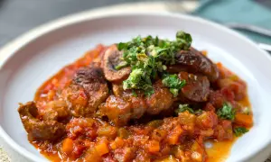 Herzhaftes Ossobuco mit einer reichhaltigen Tomaten-Gemüse-Sauce und frischer Kräuter-Gremolata als Beilage.