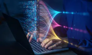 Ręce na klawiaturze laptopa, wizualizacja danych w postaci kolorowych linii i kodu binarnego. Przyszłość elektrotechniki w cyfrowym świecie.