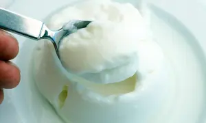 Cremiger Joghurt, eine köstliche Alternative zu saurer Sahne, wird mit einem Löffel aus einer Schüssel gehoben.