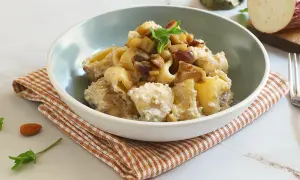 Un piatto invitante di pasta con melanzane in bianco, condita con una crema saporita e guarnita con menta fresca.