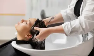 Une coiffeuse masse le cuir chevelu d'une cliente, créant une mousse onctueuse. Un moment de détente pour des cheveux sans sulfate.