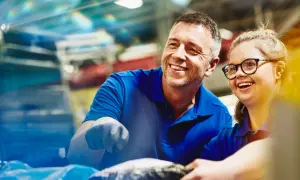 Un uomo e una donna sorridono mentre lavorano insieme. Un esempio di inclusione e pari opportunità, anche per le ferie categorie protette.
