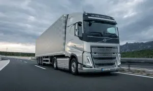 Un tracteur Volvo FH Globetrotter tracte une semi-remorque sur une autoroute. La longueur impressionnante de l'ensemble est mise en valeur par le paysage montagneux en arrière-plan.