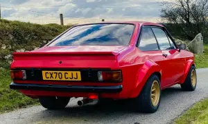 Röd Ford Escort MK2 med breddade skärmar och gul registreringsskylt.
