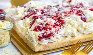 Ein köstlicher Spaghetti-Kuchen vom Blech, verziert mit Sahne, Kirschen und weißen Schokostreuseln.