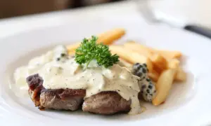 Filete de res bañado en cremosa salsa a la pimienta, acompañado de papas fritas y perejil fresco.