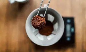 En skopa nykvarnat kaffe hälls ner i en filterhållare. Det är dags att mala eget kaffe för en perfekt bryggning.