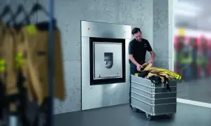 Mężczyzna wkłada ubrania strażackie do wózka obok urządzenia nomeks.