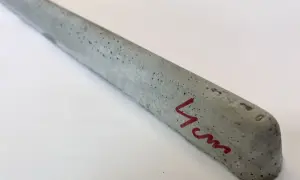 Szary, betonowy element z widocznymi pęcherzykami powietrza, oznaczony czerwonym markerem "4cm". To dystanse do zbrojenia betonowego.