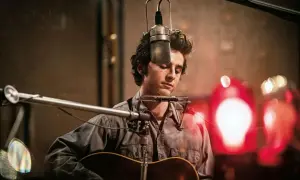 Młody muzyk z harmonijką ustną i gitarą, nagrywający w studio. Czy to on śpiewa "Blowin' in the Wind" Boba Dylana?