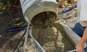 Betoniarka wylewa świeży beton do taczki.