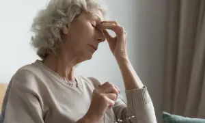 Stars w oczach? Starsza kobieta zamyka oczy, masując skronie. Może to objaw problemów ze wzrokiem, które można sprawdzić za pomocą amsler test.