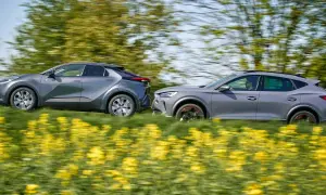 Dwa szare samochody, Toyota i Cupra, pędzą przez kwitnące pole rzepaku.