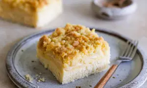 Ein Stück Blechkuchen mit Streuseln auf einem Teller, bereit zum Genießen. Dieses Rezept für Hefeteig Blechkuchen ist ein Klassiker.