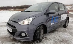 Szary Hyundai i10 na zimowych oponach, gotowy do jazdy testowej po zaśnieżonym terenie.