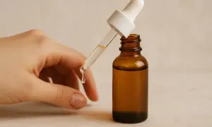Kwas traneksamowy na twarz: kropla serum z pipety spada do brązowej buteleczki.