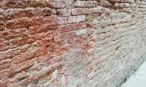 Un muro che sfarina rimedi, con mattoni rossi e bianchi consumati dal tempo, che raccontano storie antiche.