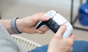 Hände halten einen weißen PS5-Controller, bereit für das PS4 auf PC streamen.