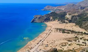 Malownicze plaże Rodos w pełnym słońcu. Błękitne morze, złoty piasek i zielone wzgórza tworzą idealne miejsce na wakacje.