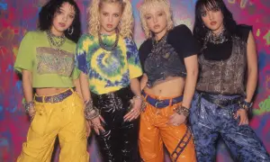 Vier junge Frauen im coolen **mode 90er jahre** Stil mit bunten Outfits und auffälligem Schmuck posieren vor einer Graffiti-Wand.
