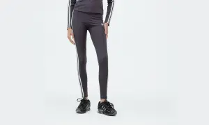 Leggings Adidas 3 stripes grigi, con logo e strisce bianche, abbinati a sneakers nere.