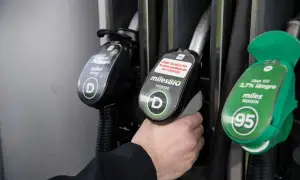 Hand håller bensinpump för miles BENSIN 95, ett alternativ till blyfri bensin. Dieselpump syns också.
