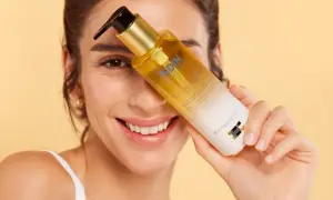 Mujer sonriente sostiene una botella de aceite de ducha ISDIN.