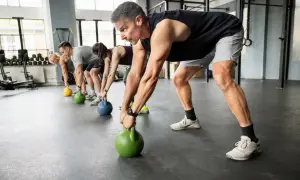 Gruppe trainiert Griffkraft mit Kettlebells. Sie heben die Gewichte vom Boden, um ihre Hände zu stärken.