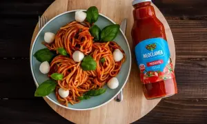 Pyszne spaghetti z kulkami mozzarelli i bazylią, obok butelka passaty pomidorowej Włocławek. Idealny składnik do sosu.