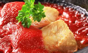 Délicieuse lotte recette en sauce tomate, garnie de persil frais. Un plat savoureux prêt à être dégusté.