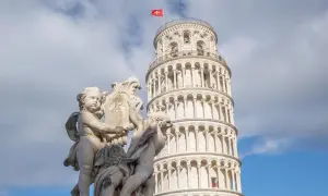 Die Torre de Pisa, ein schiefer Turm, ragt hinter einer barocken Skulptur auf.