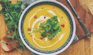 Aksamitna zupa dyniowa z mlekiem kokosowym, udekorowana świeżą kolendrą i chili. Idealna na chłodne dni.