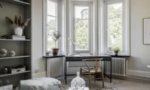 Scrivania con vista finestra, un angolo studio luminoso con sedia in legno e piante.