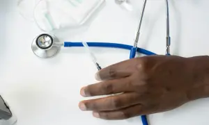 Dłoń pacjenta i stetoskop. Czy ortopeda prywatnie może wystawić zwolnienie lekarskie?