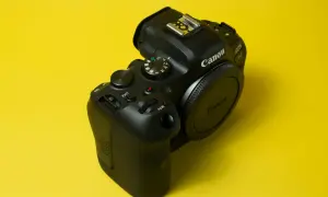 Czarny aparat Canon EOS R6 na żółtym tle. Pokrętło trybów pozwala na preselekcję czasu, ułatwiając kontrolę nad ekspozycją.