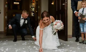 Panna młoda i pan młody zbierają płatki róż po ceremonii ślubnej.