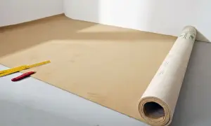 Werkzeug liegt bereit für das Teppich verlegen. Ein Teppichboden wird ausgerollt, daneben ein Zollstock und ein Cuttermesser.