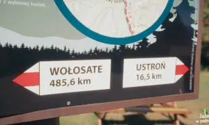 Tablica informacyjna na głównym szlaku bieszczadzkim. Wskazuje odległości do Wołosate (485,6 km) i Ustronia (16,5 km).