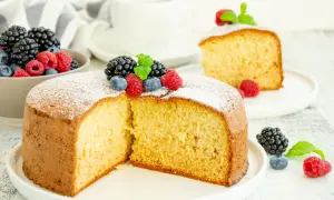 Torta soffice allo yogurt greco, decorata con frutti di bosco freschi e una spolverata di zucchero a velo.