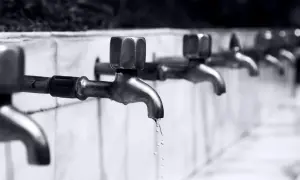 Reihe von Wasserhähnen, aus denen Tropfen fallen.