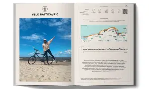 Rowerzystka na plaży z rowerem, obok mapa i opis trasy Velo Baltica/R10, jednej z najpiękniejszych ścieżek rowerowych Polska.