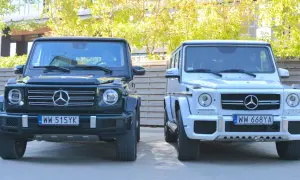 Dwa luksusowe Mercedesy klasy G, czyli gelendy, stoją obok siebie. Jedna jest ciemnozielona, druga biała.