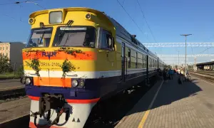 Gelber Zug mit grüner Deko am Bahnhof, bereit für die Fahrt von Riga nach Tallinn.