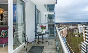 Balkon z widokiem na Gdańsk Przymorze. Stolik z kawą i kwiatami czeka na gości.