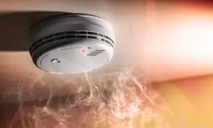 Détecteur de fumée au plafond, avec une petite lumière rouge allumée. Comment savoir si mon détecteur de fumée fonctionne ? La fumée tourbillonne en dessous.