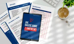 Jak radzić sobie z gniewem? Poradnik na tablecie, obok kubek kawy i słuchawki.